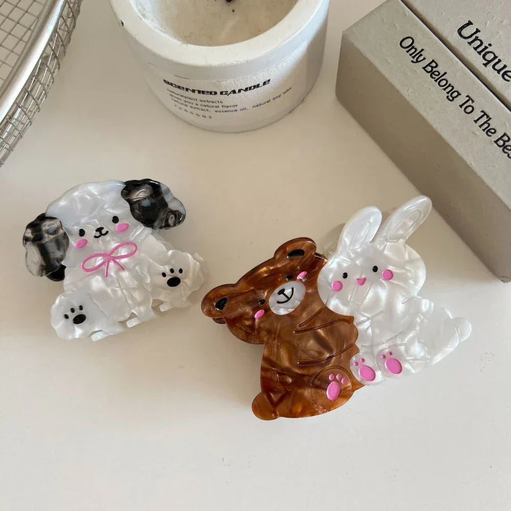 A close-up of three decorative hair claw clips shaped like a dog, a bear, and a bunny.