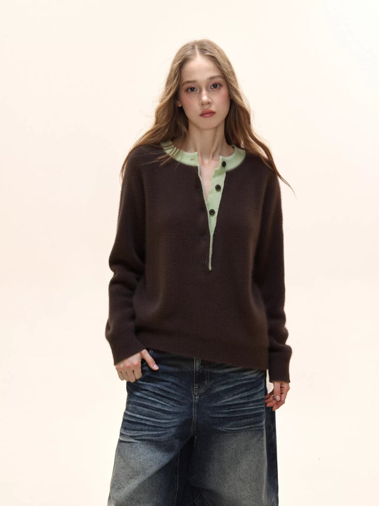 Woman wearing a brown knit henley sweater with a light green collar and dark wash wide-leg jeans.
