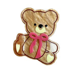 A single beige teddy bear hair clip with a pink bow and heart details.