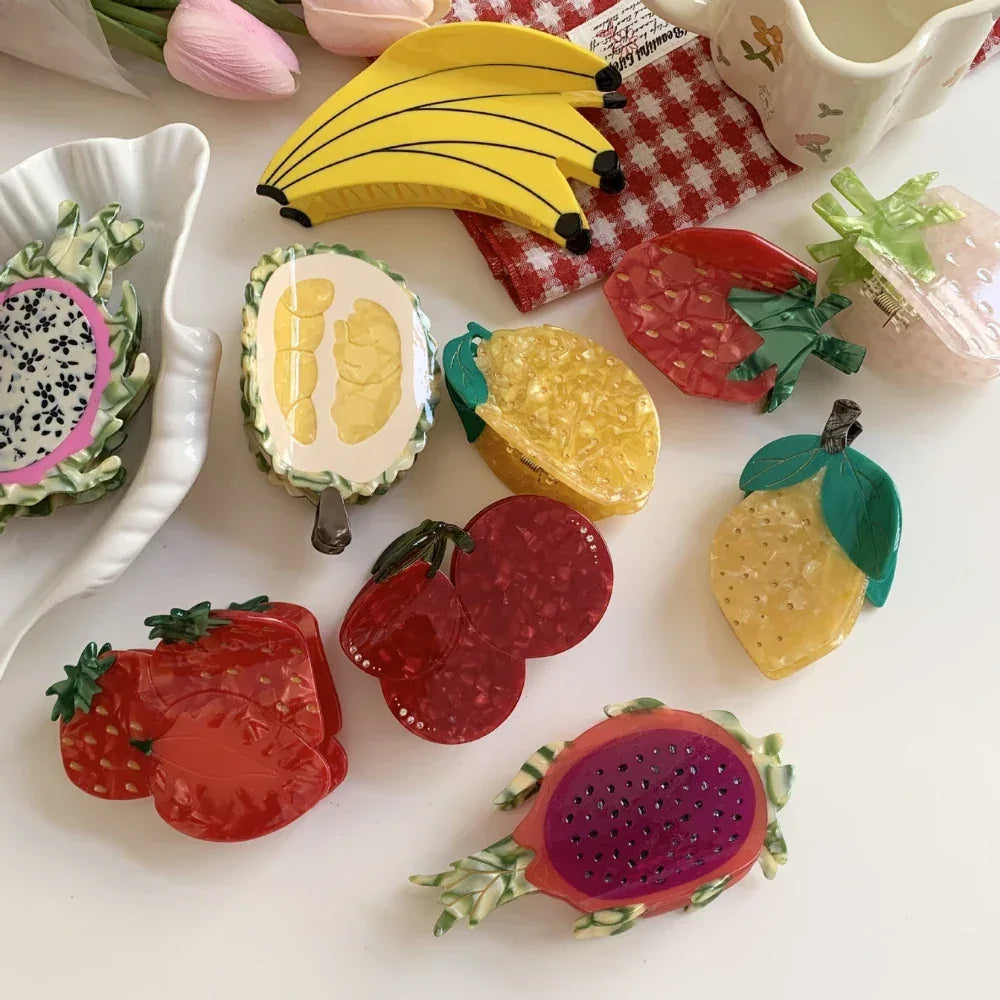 A flat lay of various fruit-themed hair clips, showcasing a banana bunch as the centerpiece.