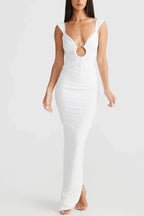 Woman wearing a long white sleeveless dress with a plunging V-neck and a cutout detail at the bust.
