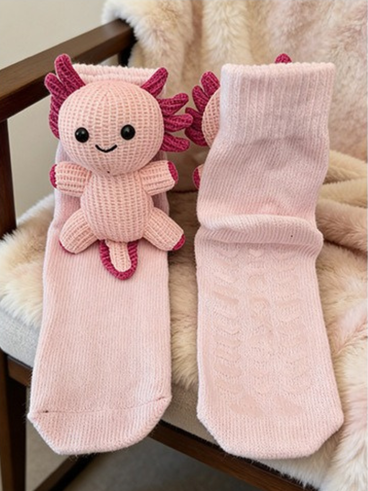 Two light pink ribbed socks with pink axolotl appliques are displayed side-by-side on a fuzzy surface.