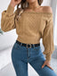 Woman wearing a tan off-the-shoulder cable knit cropped sweater with blue jeans and a black belt.