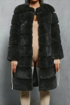 Woman wearing a dark gray faux fur coat over a beige bodysuit and thigh-high socks.