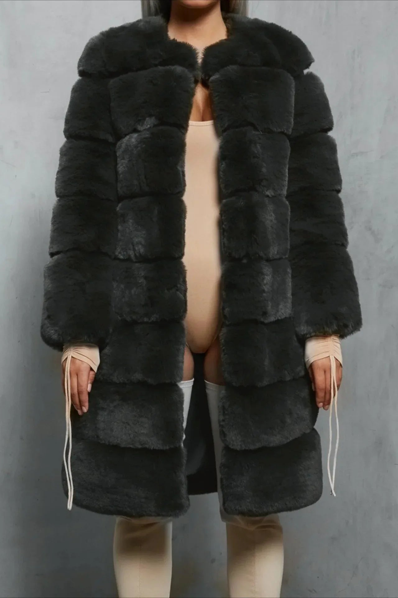 Woman wearing a dark gray faux fur coat over a beige bodysuit and thigh-high socks.