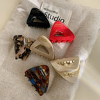 Close-up view of six triangular hair clips with differing patterns and solid colors on a neutral fabric background