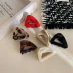 Assortment of triangular hair clips in different hues and designs, displayed on a light-colored cloth
