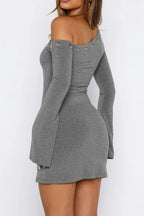 Back view of a woman wearing a grey one-shoulder dress with flared sleeves and grommet details.