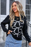 woman wearing black crew neck sweater with white bow pattern and blue jeans