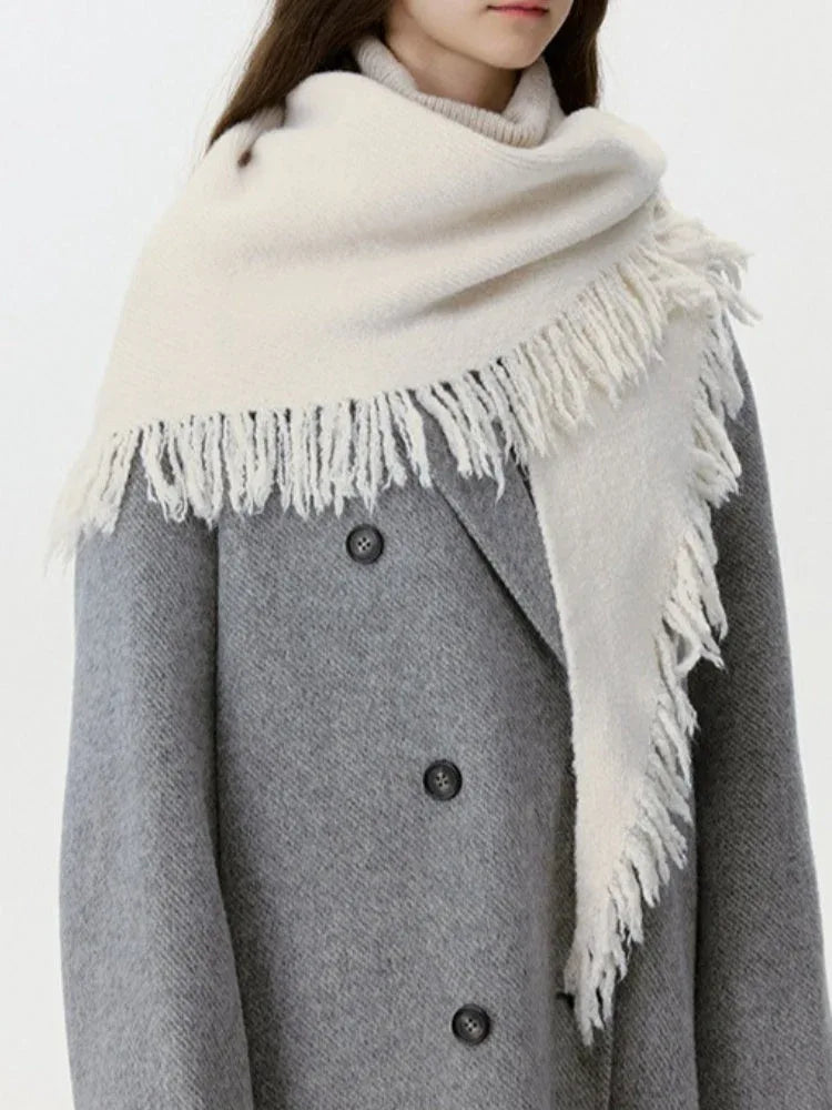 Model in a grey coat with a cream-colored fringed scarf
