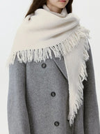 Model in a grey coat with a cream-colored fringed scarf