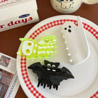 Halloween hair clips including a skeleton cat, ghost, and bat on a plate with a red and white checkered rim