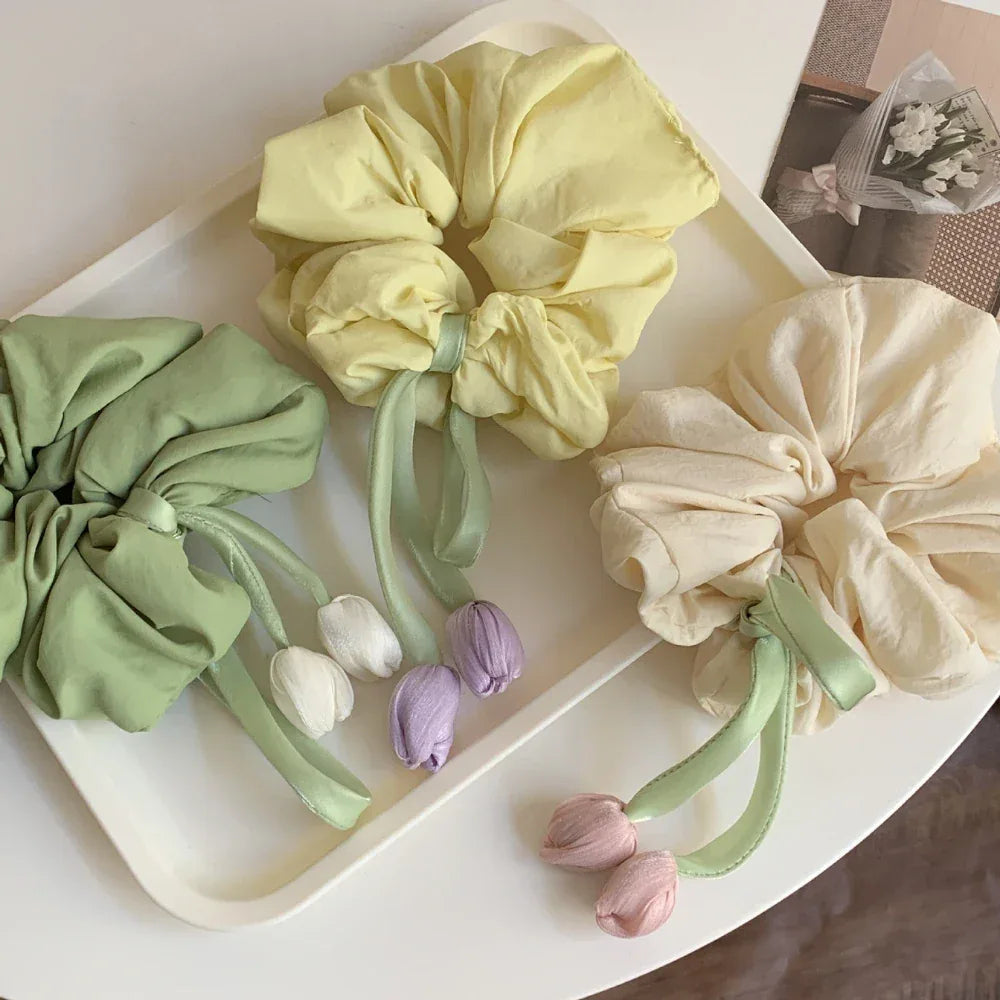 three pastel scrunchies with tulip embellishments on a white tray