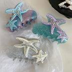 Three glitter hair claw clips with starfish and rhinestone embellishments in blue/pink, purple/teal, and silver/white colorways.