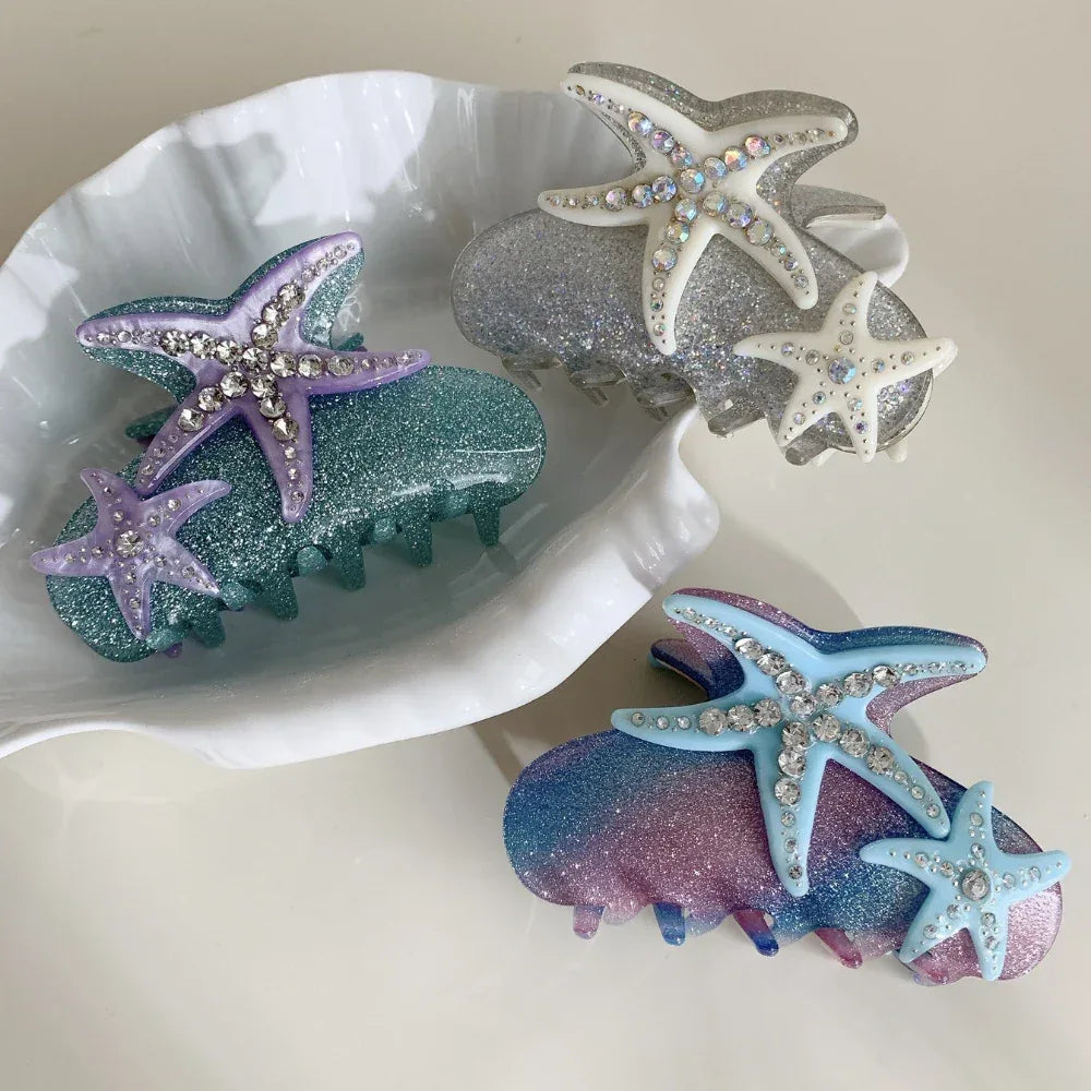 A top-down view of three decorative hair claw clips, showcasing their glittery texture and starfish designs.