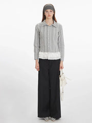 Woman wearing a long-sleeved plaid collared shirt with a white ruffled hem, black wide-leg pants, and a white handbag.