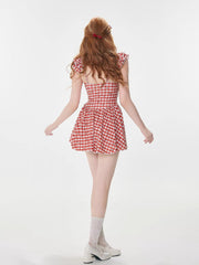 Rear view of a woman wearing a red and white gingham dress with ruffled sleeves.