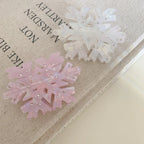 Two snowflake hair clips, one pink and one white, on top of a book
