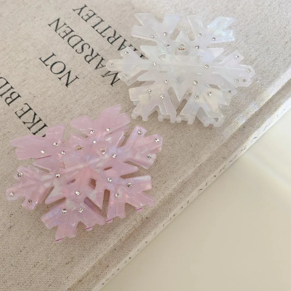 Two snowflake hair clips, one pink and one white, on top of a book
