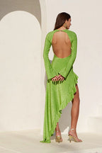 Woman wearing a lime green metallic knit dress with an asymmetrical ruffled hemline and an open back, shown from the back.