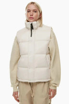 Woman wearing a cream puffer vest over a cream sweatshirt and tan cargo pants