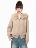 Woman wearing a beige knit cardigan with a faux fur collar and blue jeans, front view