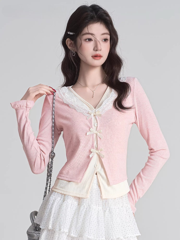 Close-up of a woman wearing a pink V-neck knit cardigan with lace trim and bow closures, showing the details of the garment.