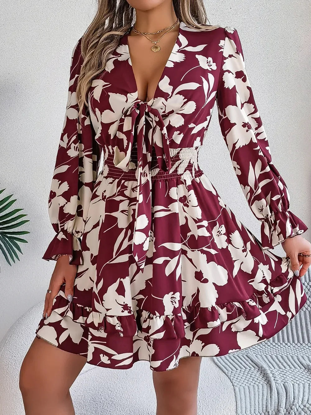 woman wearing a burgundy floral print mini dress with bishop sleeves and a tie front