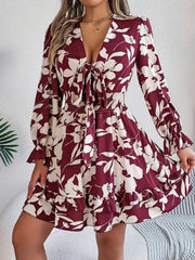 woman wearing a burgundy floral print mini dress with bishop sleeves and a tie front