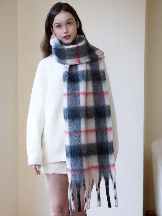 Full body shot of a woman wearing a cream-colored sweater and a long plaid scarf.