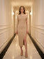 woman standing in a hallway wearing a beige asymmetrical ribbed knit midi dress with a high slit