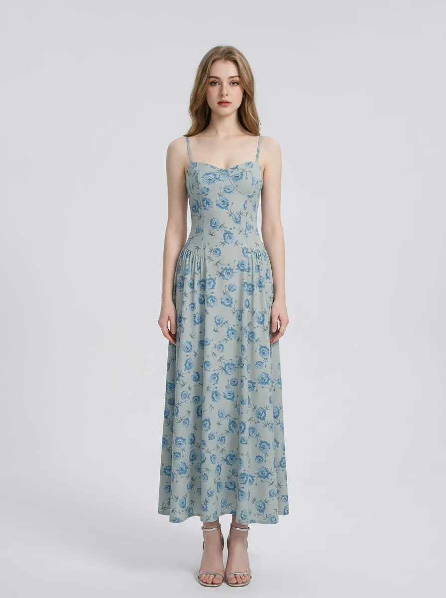 Woman wearing a light blue floral print midi dress with spaghetti straps.