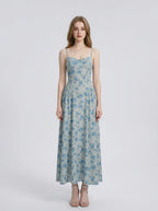 Woman wearing a light blue floral print midi dress with spaghetti straps.