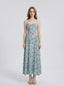 Woman wearing a light blue floral print midi dress with spaghetti straps.