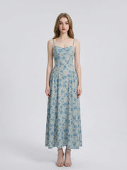 Woman wearing a light blue floral print midi dress with spaghetti straps.