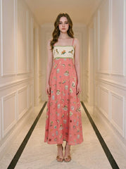 Woman in a coral A-line midi dress with spaghetti straps and a square neckline, standing in a hallway.