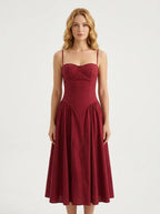 Woman wearing a deep red fit and flare midi dress with spaghetti straps, front view
