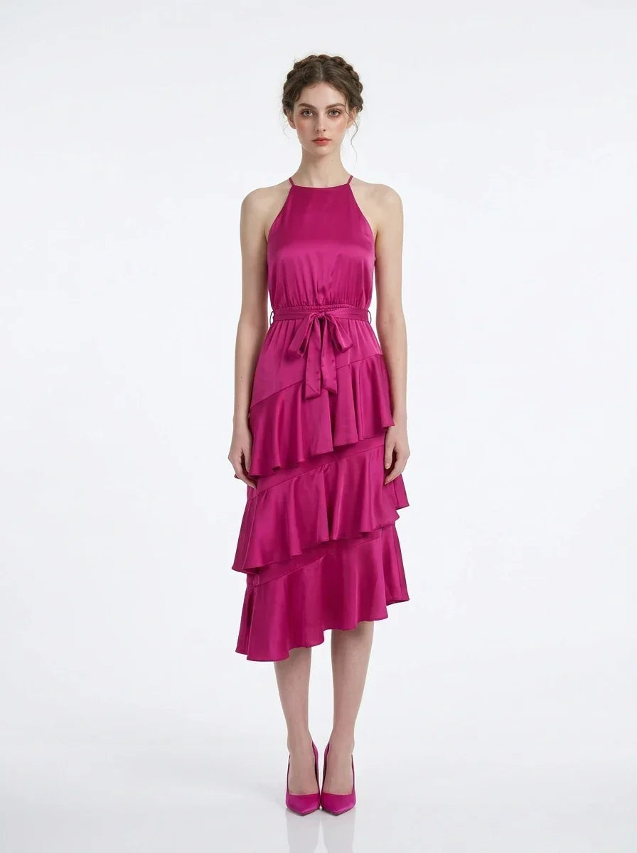 Woman wearing a fuchsia satin halter tiered midi dress with a self-tie belt.