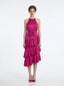 Woman wearing a fuchsia satin halter tiered midi dress with a self-tie belt.