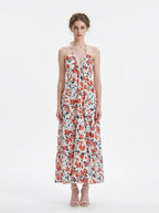 Woman wearing a white floral print maxi dress with a halter neckline and tiered skirt, standing against a white background.