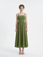 Woman wearing a green linen midi dress with a smocked bodice and square neckline, standing against a white background.