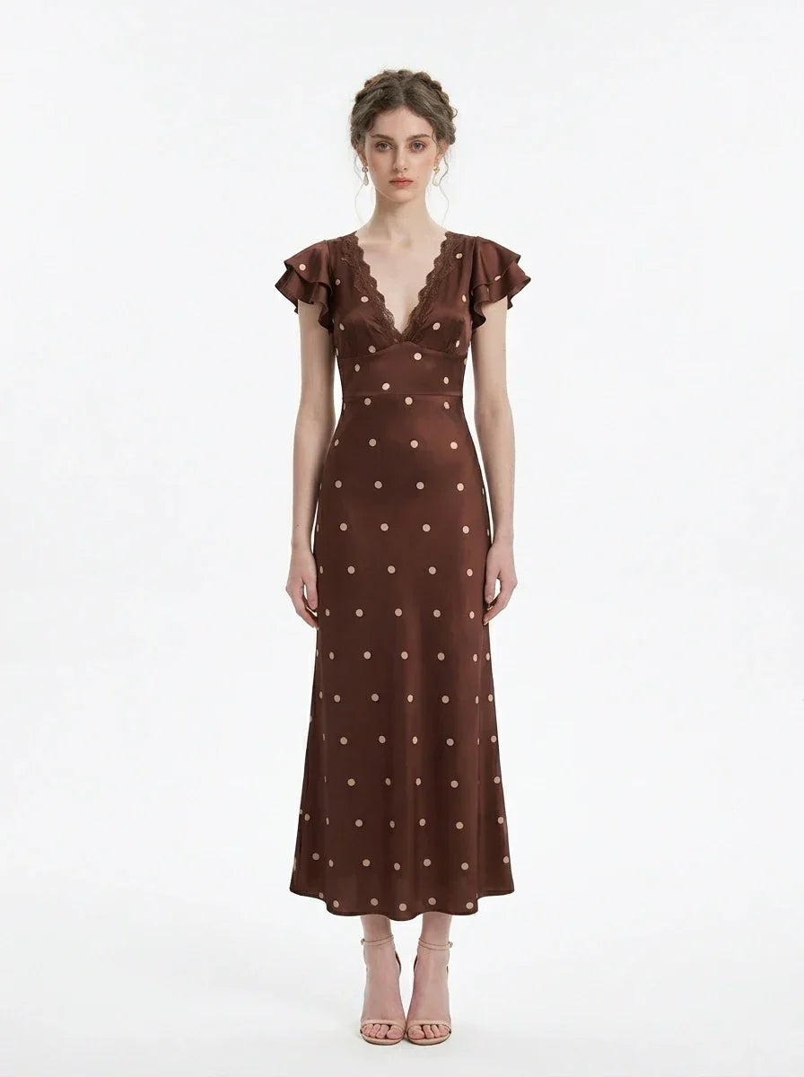 Woman wearing a brown polka dot midi dress with ruffled sleeves and a v-neckline, standing against a white background.