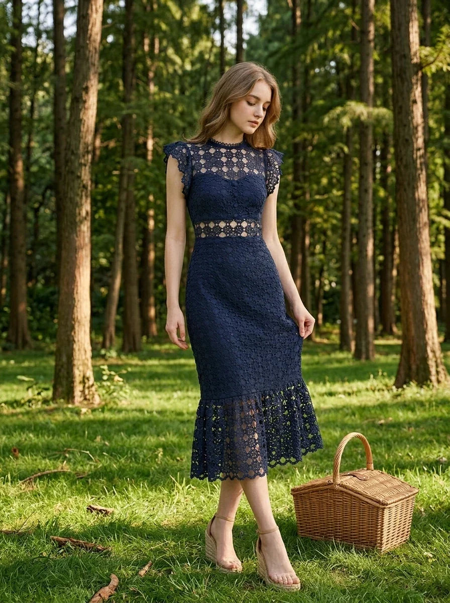 Woman in a navy blue lace mermaid dress with a high neck and cap sleeves, standing in a forest with a picnic basket.