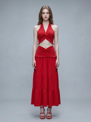 Woman wearing a red halter crop top and a tiered maxi skirt, front view