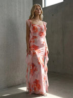 Woman posing in a pink floral print maxi dress with ruffle trim indoors