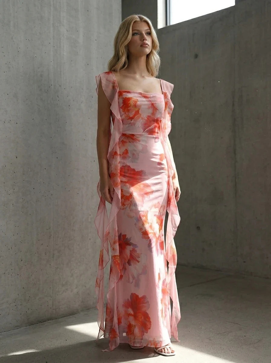 Woman posing in a pink floral print maxi dress with ruffle trim indoors