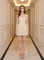 Woman wearing a yellow floral print mini dress with spaghetti straps and a sweetheart neckline standing in a hallway.