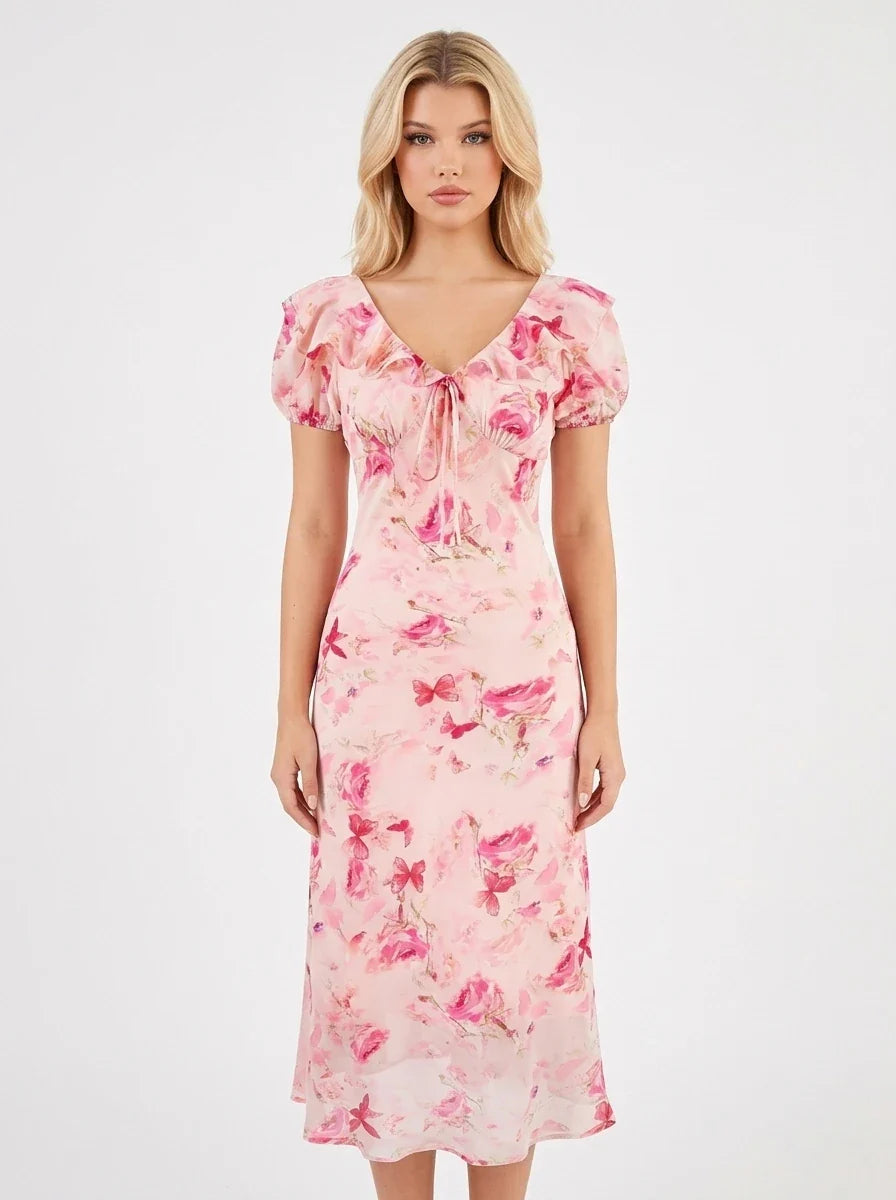 Woman wearing a pink floral print midi dress with short puff sleeves and a tie-front V-neckline, shown from the front.