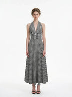 Woman wearing a black and white gingham halter maxi dress, front view
