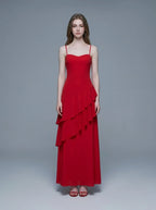 Woman wearing a red floor-length chiffon dress with tiered ruffles and spaghetti straps, front view.